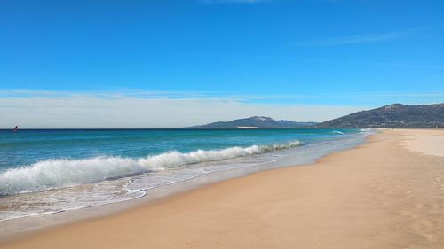 Scenic view of beach against blue sky