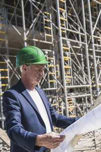 Engineer wearing hardhat analyzing plans at construction site