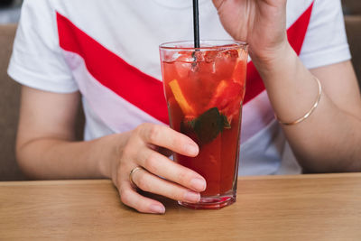 Midsection of man holding drink on table