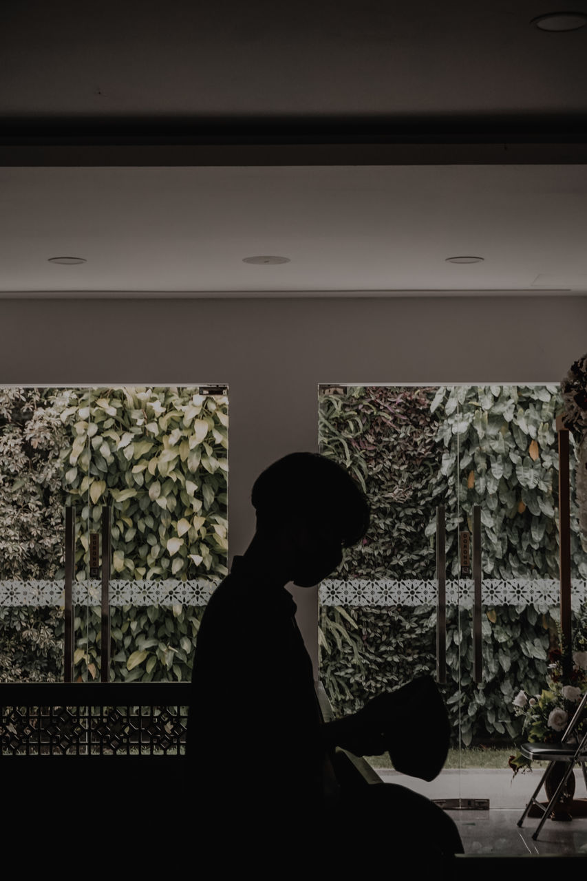 SILHOUETTE OF MAN LOOKING AT WINDOW