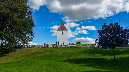Ullits church by lawn against cloudy sky