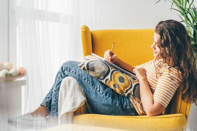 Young woman using laptop while sitting on sofa at home