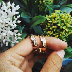 Cropped hand holding wedding rings by flowers