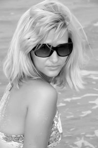 Portrait of beautiful woman wearing sunglasses against sea