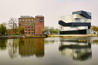 Reflection of building in lake against clear sky