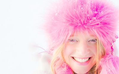 Close-up portrait of smiling woman wearing fur coat during winter against white background