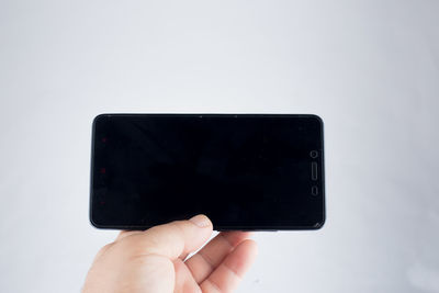 Close-up of hand holding smart phone against white background