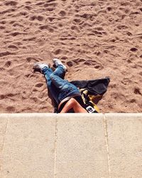 Low section of man relaxing below retaining wall at beach