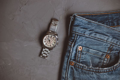 Directly above shot of wristwatch and jeans on gray background
