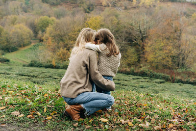 Rear view of a mother hugging her daughter on a walk.