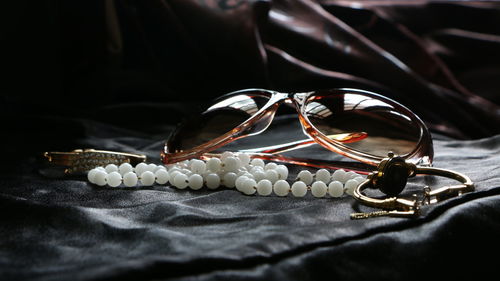 Close-up of pearl necklace with sunglasses and watch on table