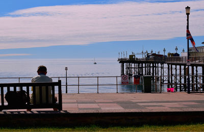 Rear view of man standing by railing against sea