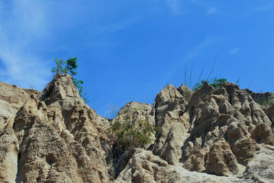 Low angle view of rocks against blue sky