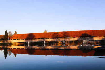 Reflection of buildings in lake against clear sky