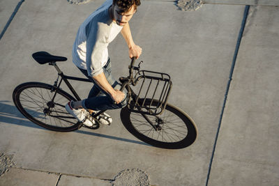 Young man riding commuter fixie bike on concrete slabs