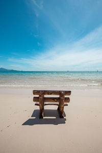 Deck chairs on beach against sky