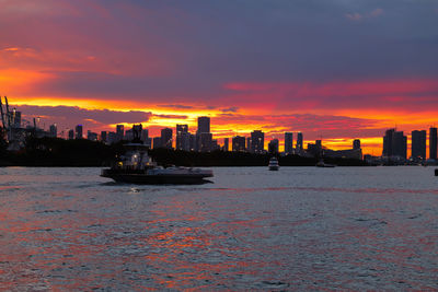 Scenic view of sea by buildings against sky during sunset