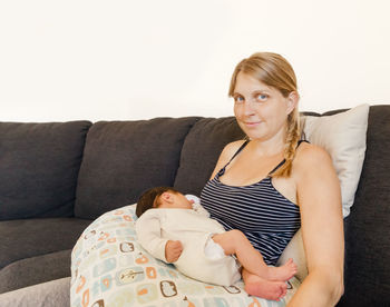 Beautiful woman with daughter sitting on sofa