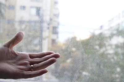 Midsection of person seen through wet glass window in rainy season