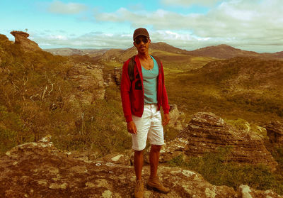 Full length portrait of man standing on mountain against sky