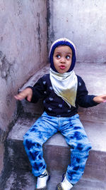 Portrait of cute boy sitting against wall