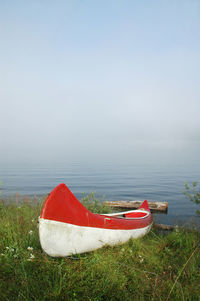 Red boat moored on beach against sky