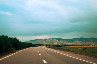 Road leading towards mountains against sky