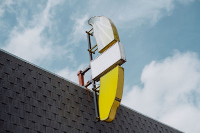 Low angle view of a banana neon light sign on building against sky