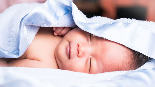 Close-up of newborn baby boy sleeping on bed at home