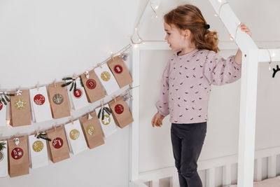 Toddler child gets new advent calendar task, waiting for christmas. festive mood for cute curly girl