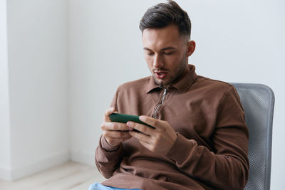 Young man using mobile phone while sitting on sofa at home