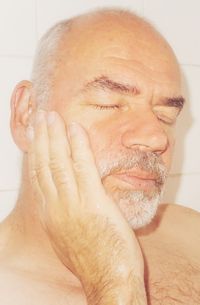 Close-up of serious man with eyes closed against wall