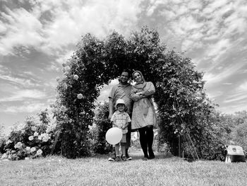 Man and woman standing by tree against sky