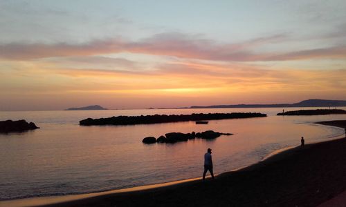 Silhouette woman standing by sea against sky during sunset