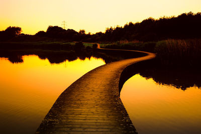 Pier over calm lake during sunset