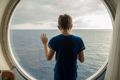 Boy looking at sea against sky