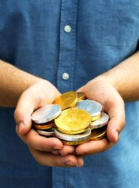 Midsection of man holding gold and silver chocolates