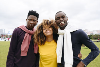 Smiling multiracial friends in front of sky at park