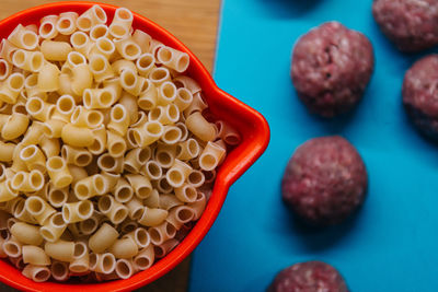 Close-up of raw pasta in saucepan by meatballs on table