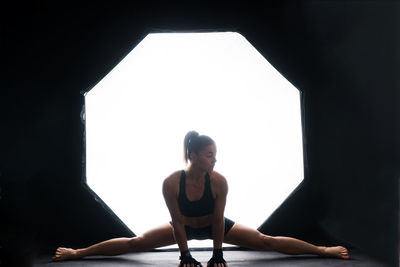 Full length of young woman exercising at home