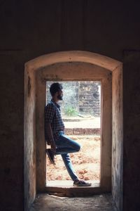 Side view full length of man standing at doorway