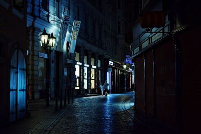 Illuminated street amidst buildings at night