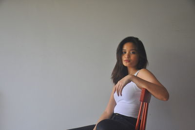 Portrait of girl sitting against wall