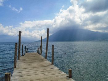 Wooden pier over sea against sky