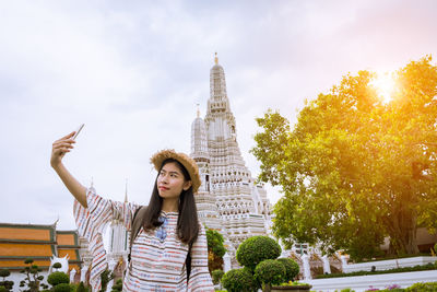 Woman taking selfie while standing against temple in city