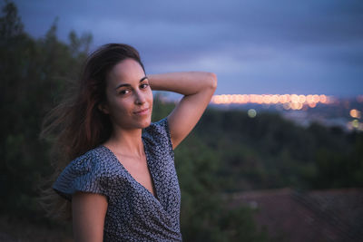 Portrait of young woman standing against sky