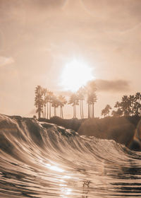 Scenic view of waves against sky during sunset