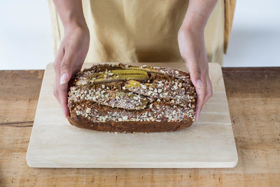 Woman hand holding banana bread at wood table.