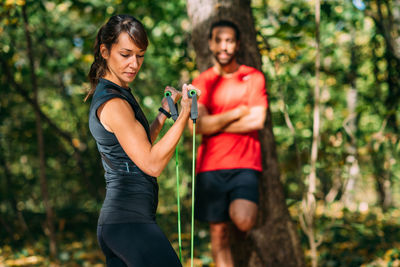Young couple exercising with elastic resistance bands in a park