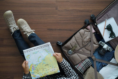 Low section of woman holding map while sitting on floor